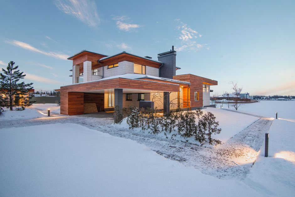 Exterior view of luxurious residential house with roofed parking and spacious backyard